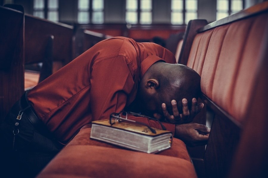 man praying on church bench